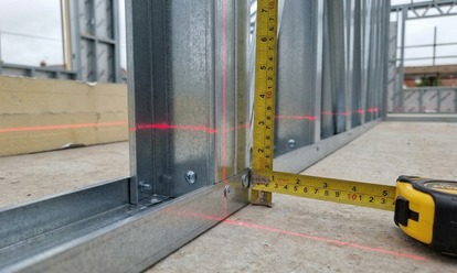 Close-up of steel studs, track and fixings with a laser level on site